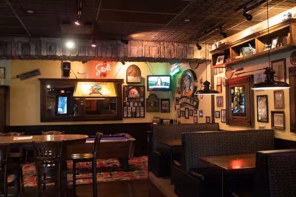 Dimly lit pub interior with dining booths, tables, and a pool table.