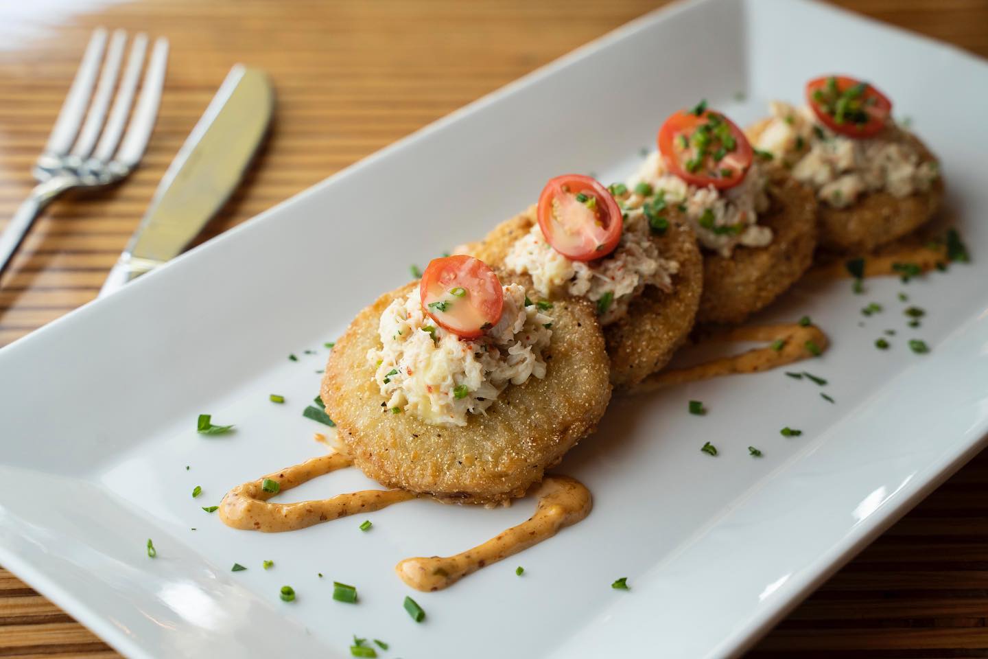 Fried green tomatoes topped with crab salad, cherry tomatoes, and chives.