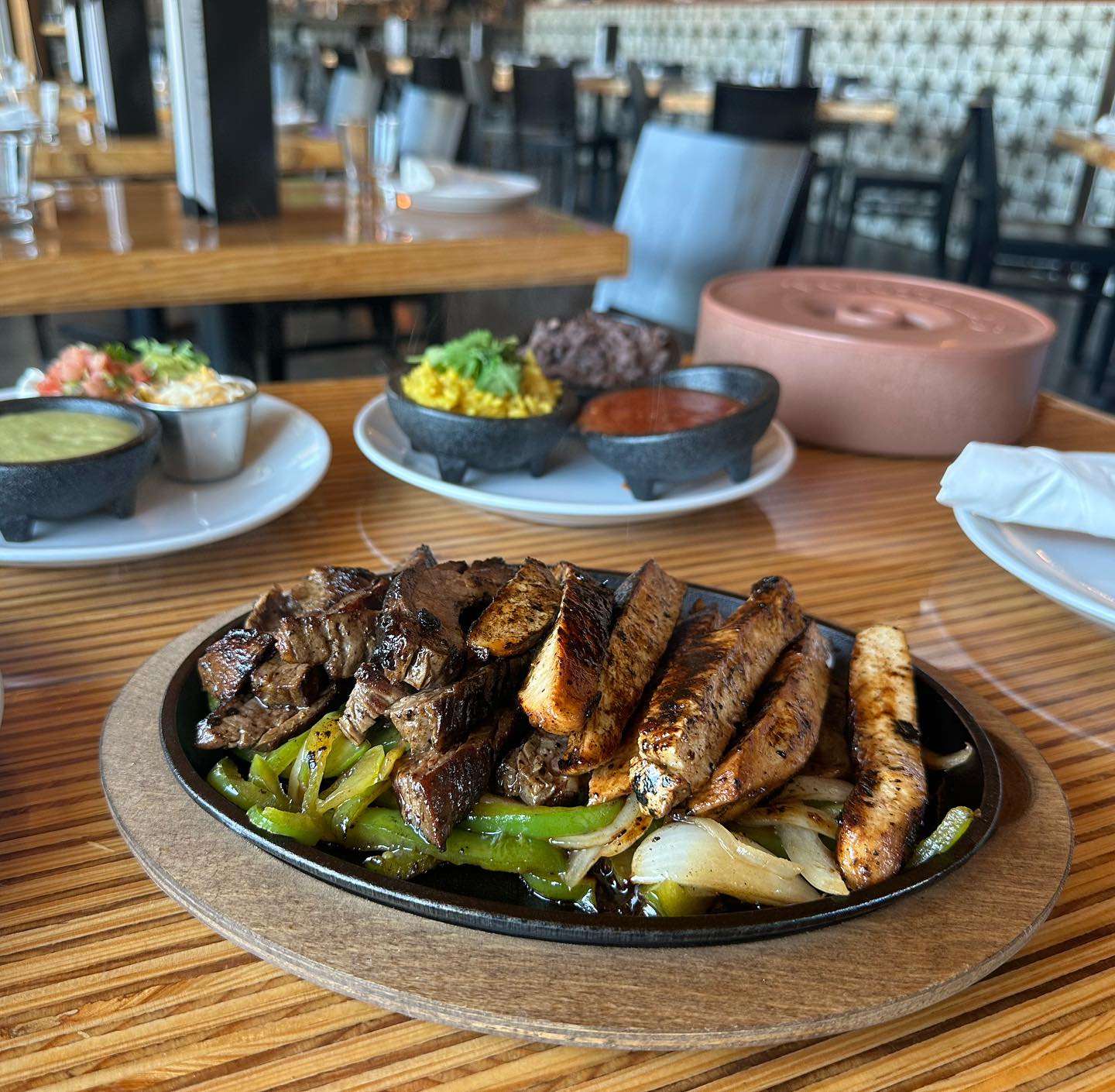 Fajita plate with steak, chicken, peppers, onions, and small sides.