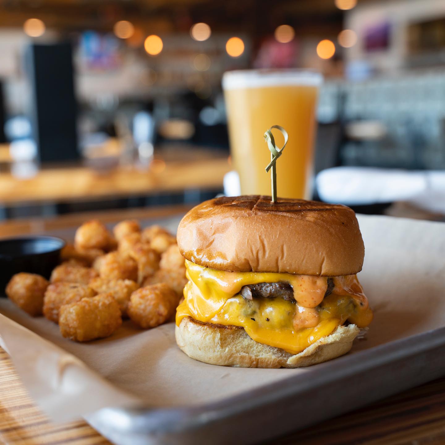 Double cheeseburger with melted cheese, tater tots, and a beer.