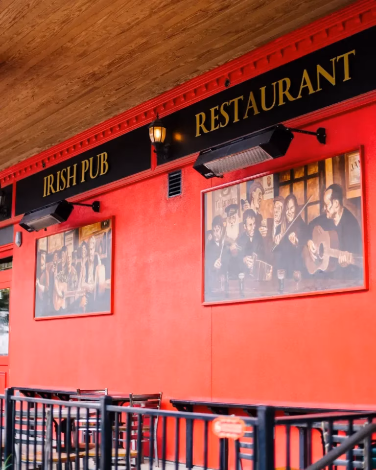 Red building exterior with 'Irish Pub Restaurant' sign and musician paintings.