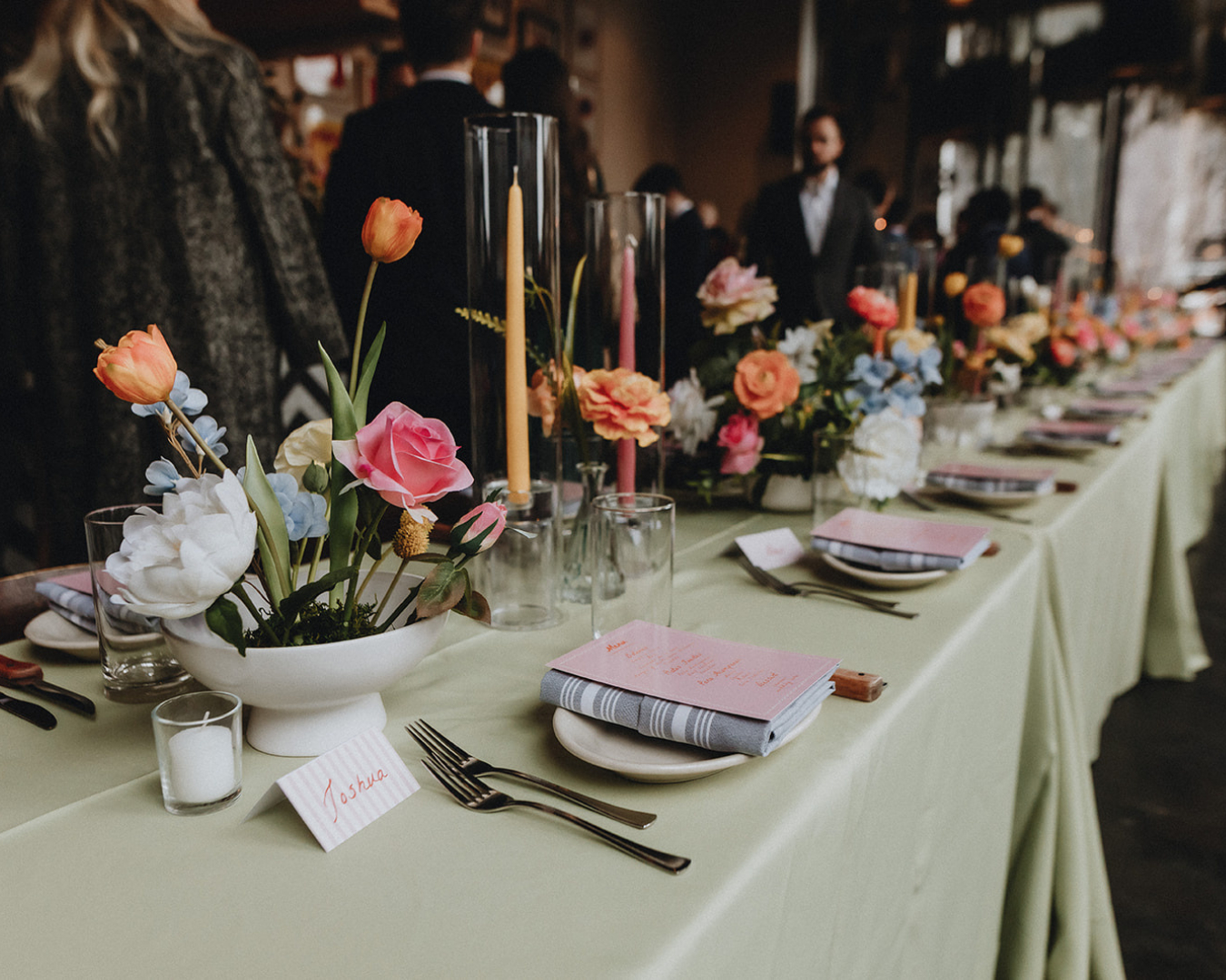 Event table set with colorful floral arrangements, candles, and place settings.