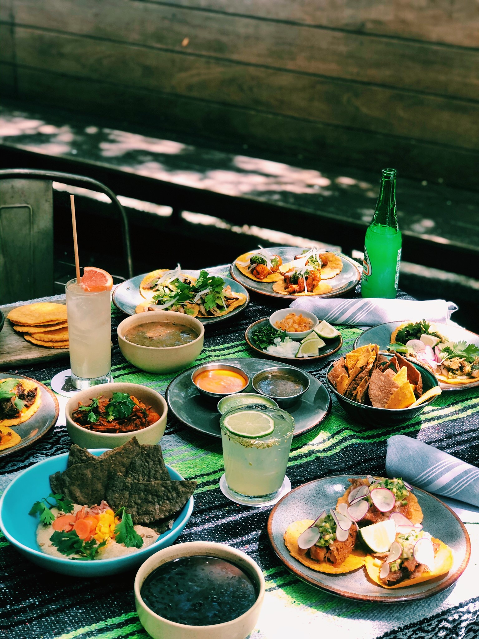 Many colorful Mexican dishes and drinks on a striped table.