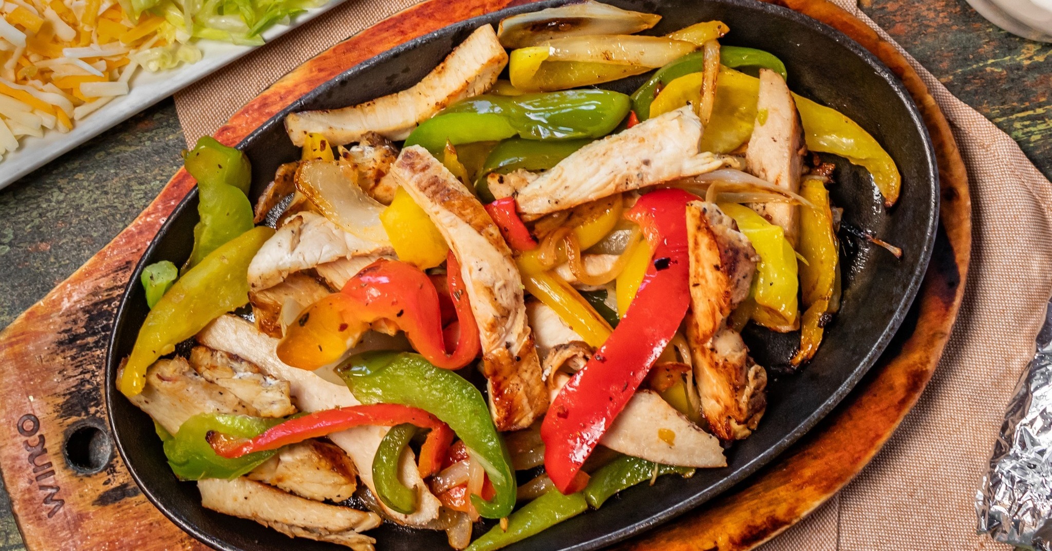 Chicken fajitas with colorful bell peppers and onions on a skillet.