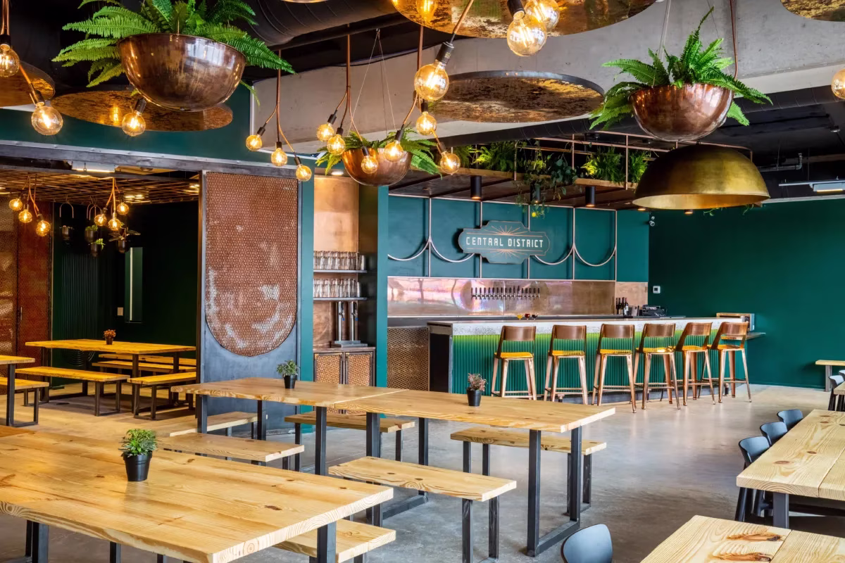 Central District restaurant interior with wooden tables, green walls, and bar.