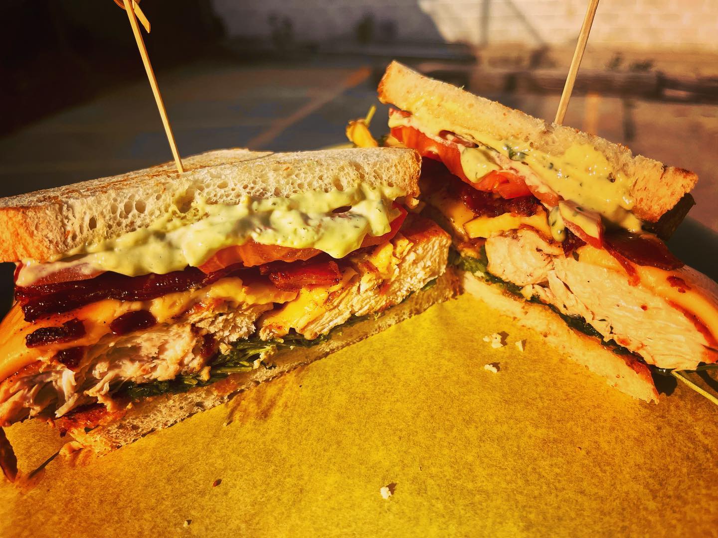 Two halves of a layered chicken, bacon, and cheese sandwich.