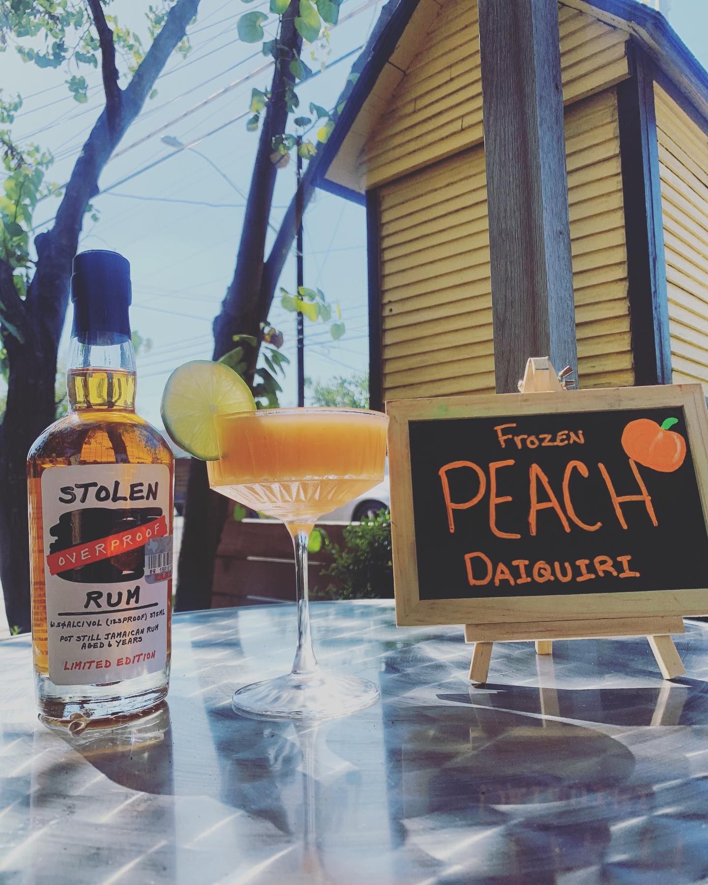 Stolen rum bottle, frozen peach daiquiri, and chalkboard sign.