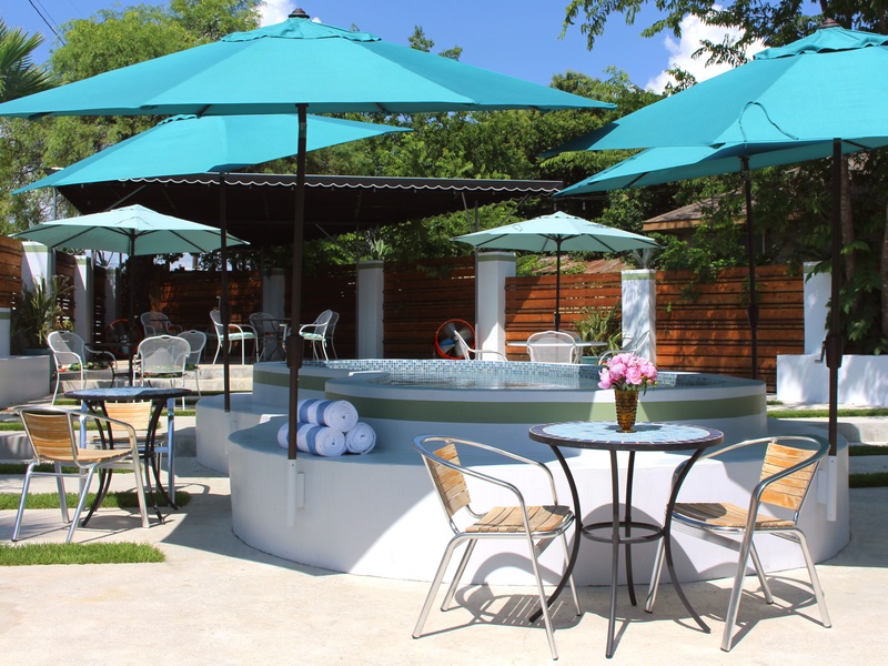 Outdoor patio with turquoise umbrellas, tables, chairs, and a circular water feature.