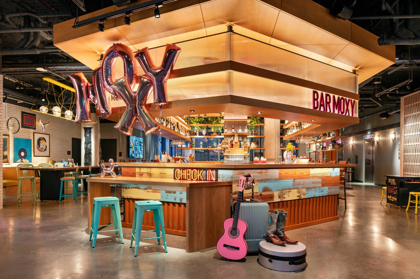 Interior of Bar Moxy, a hotel lounge and check-in counter.