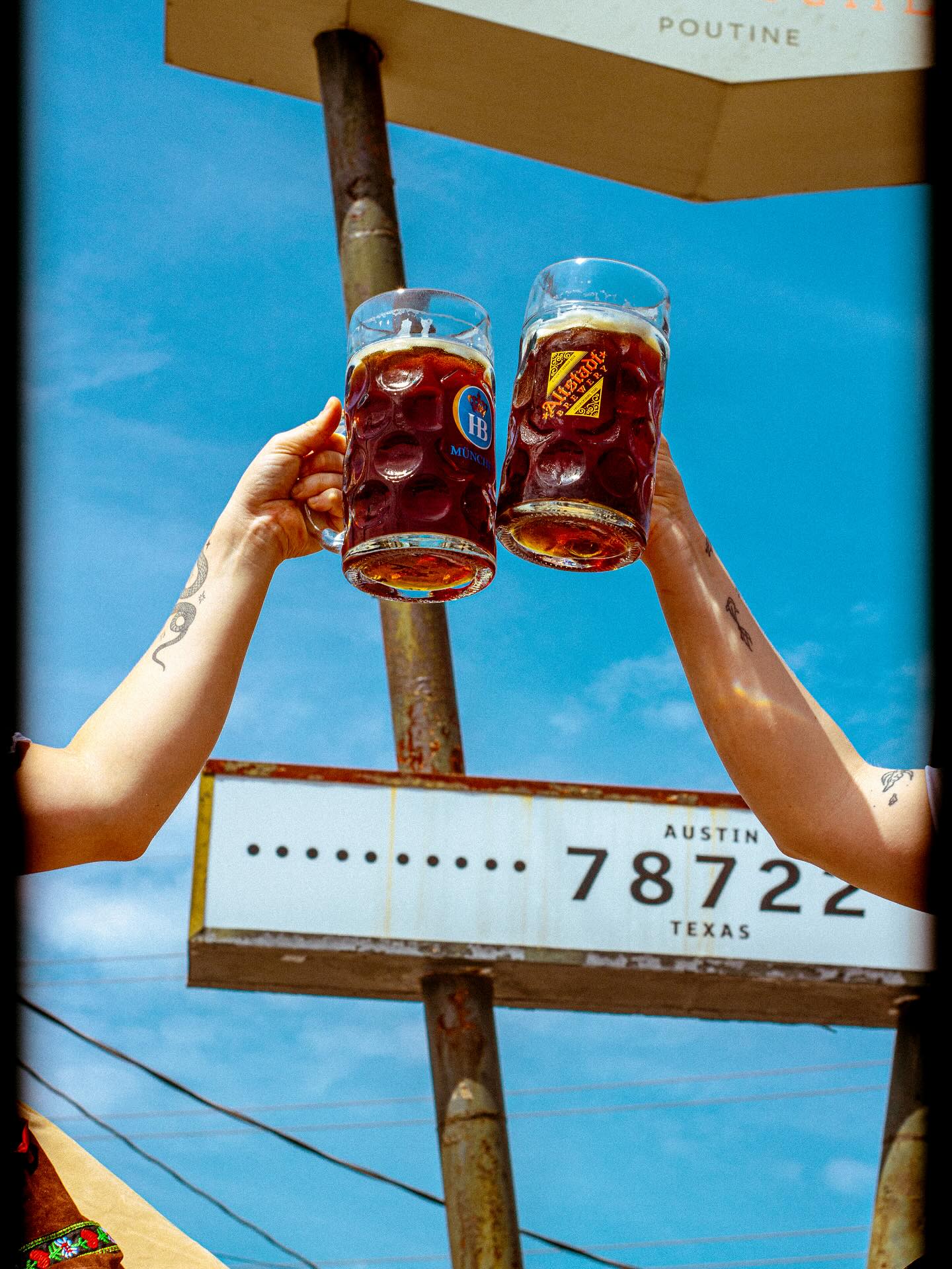 Two hands holding beer steins under a sign for Austin, Texas.