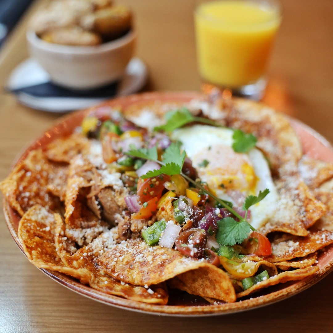 Crispy tortilla chips topped with fried egg, salsa, and orange juice.