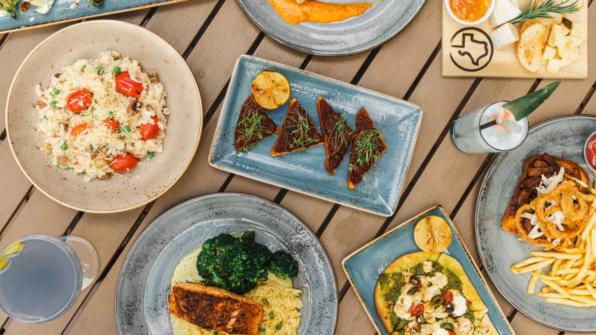 Assortment of prepared dishes, appetizers, and cocktails on a wooden table.