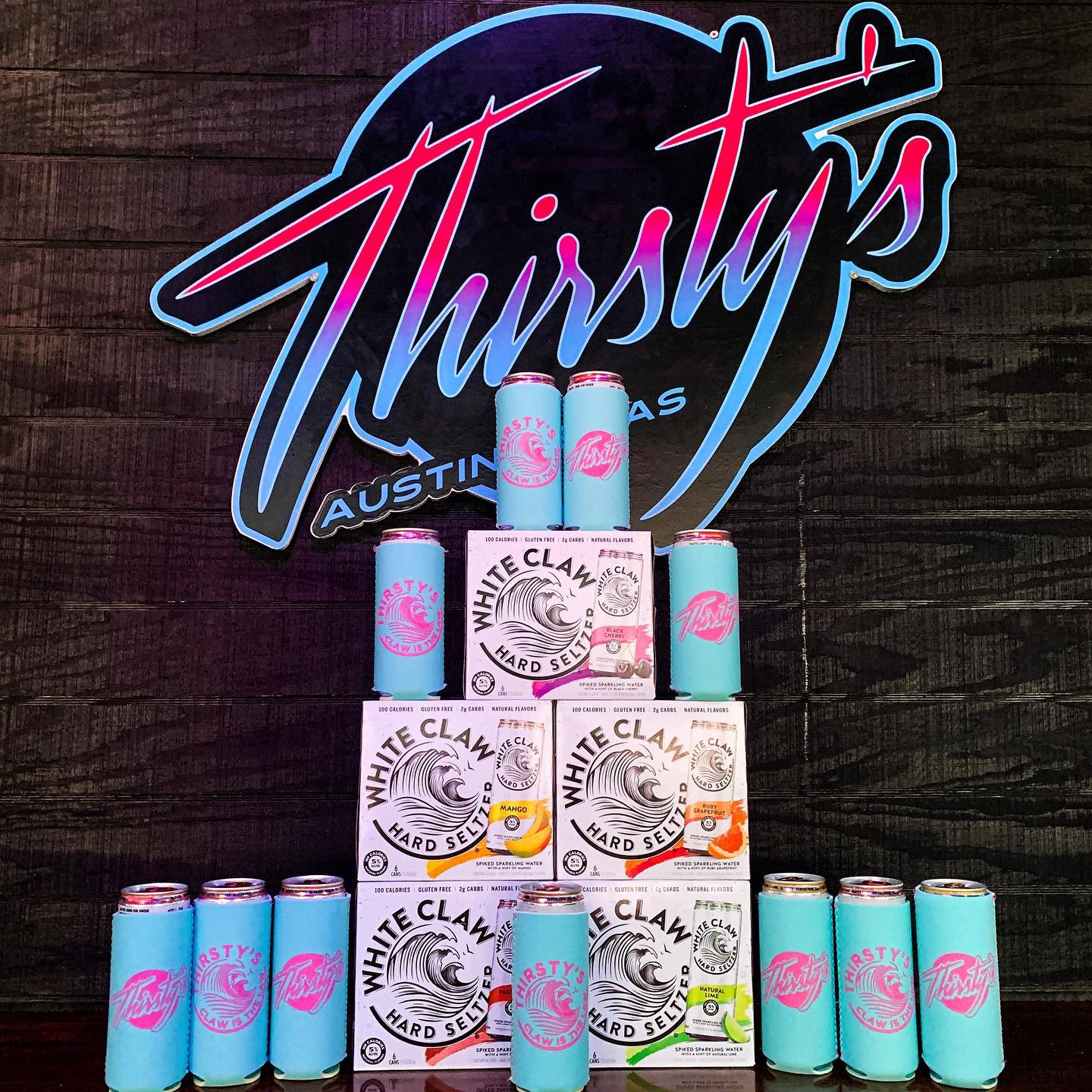 Thirsty's neon sign over White Claw hard seltzer with branded koozies.