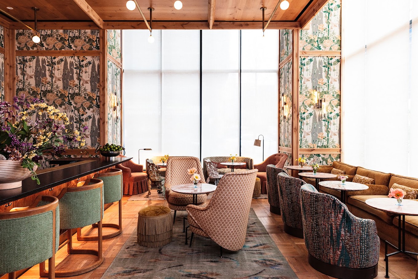 Lounge bar interior with floral wallpaper, wood ceiling, and diverse seating.