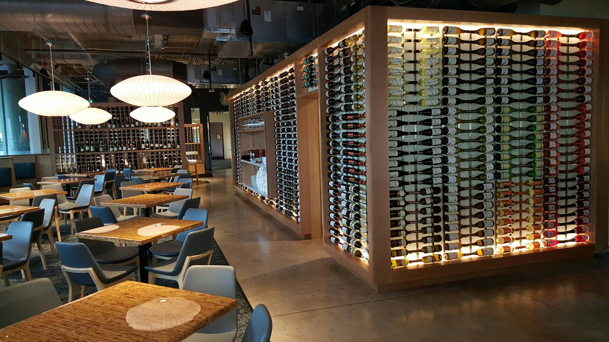 Modern dining space featuring extensive wine displays and pendant lights.