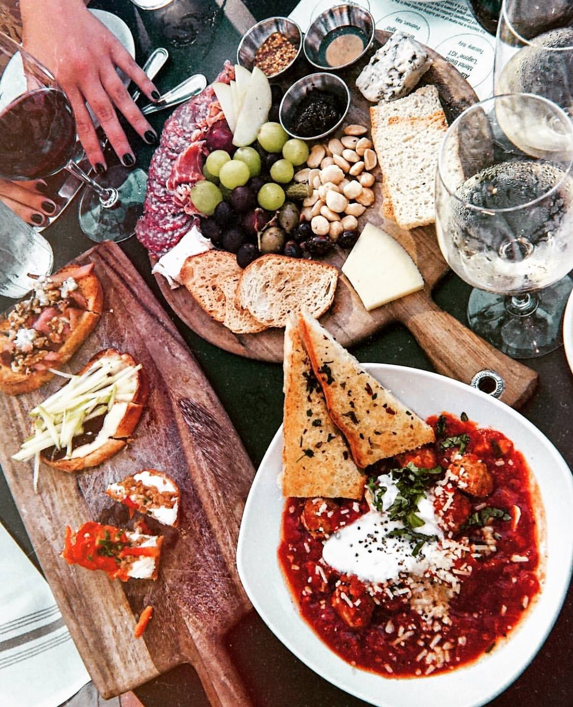 Overhead view of a table laden with charcuterie, meatballs, and wine.