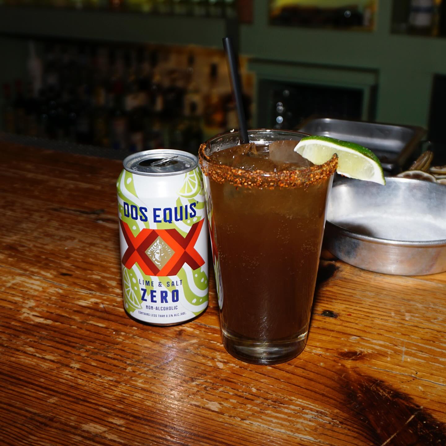 Dos Equis non-alcoholic beer can and a spiced drink with lime.