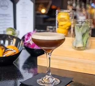 Dark brown frothy cocktail in a stemmed coupe glass.