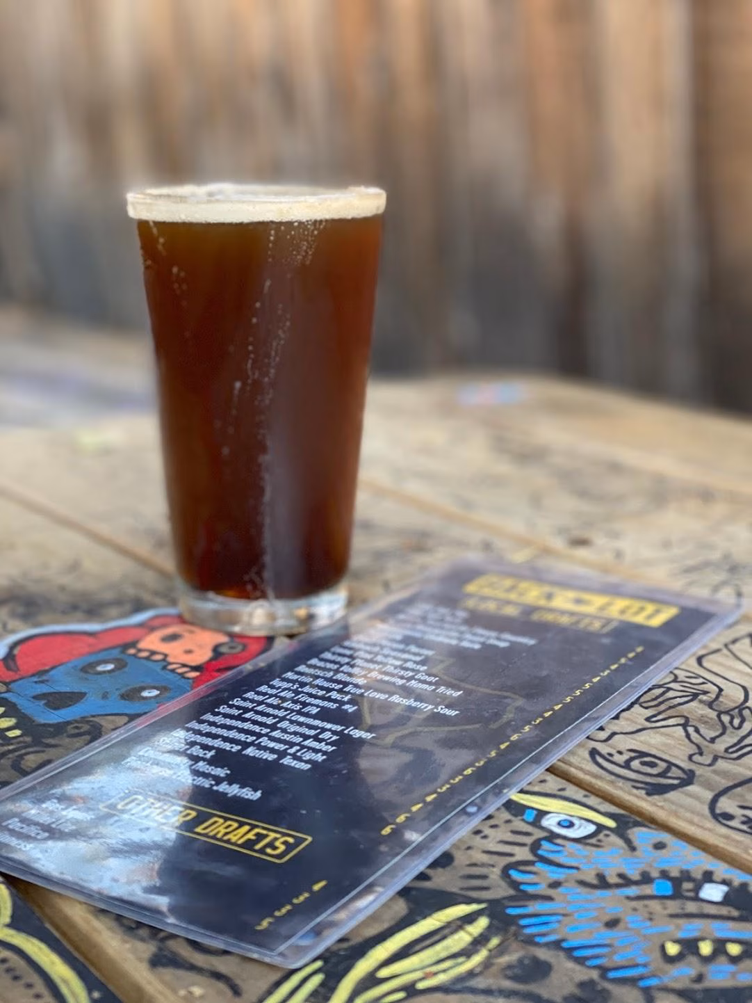 Glass of dark beer with menu on a decorated wooden table.