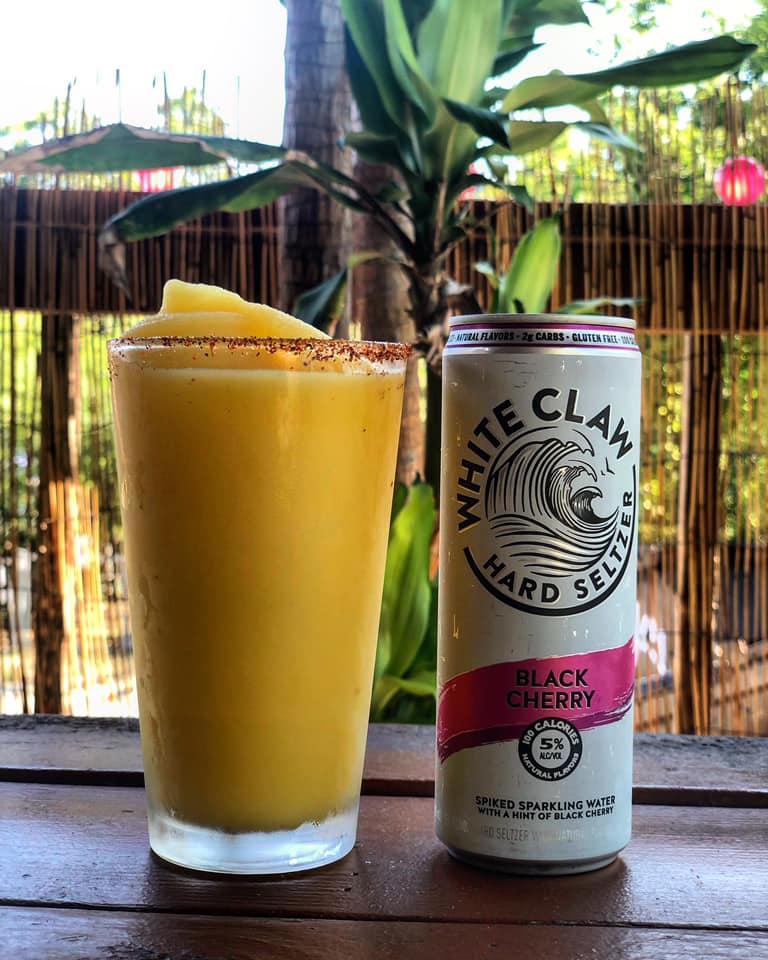 Yellow frozen drink with a spiced rim and White Claw Black Cherry.