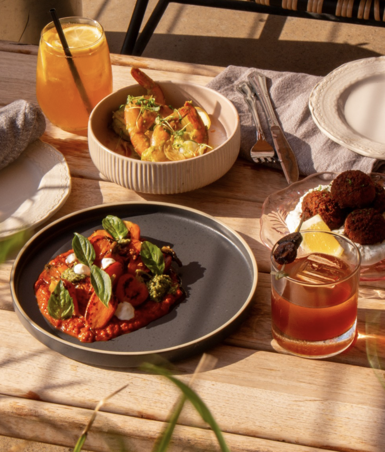 A table with various dishes and drinks in bright sunlight.