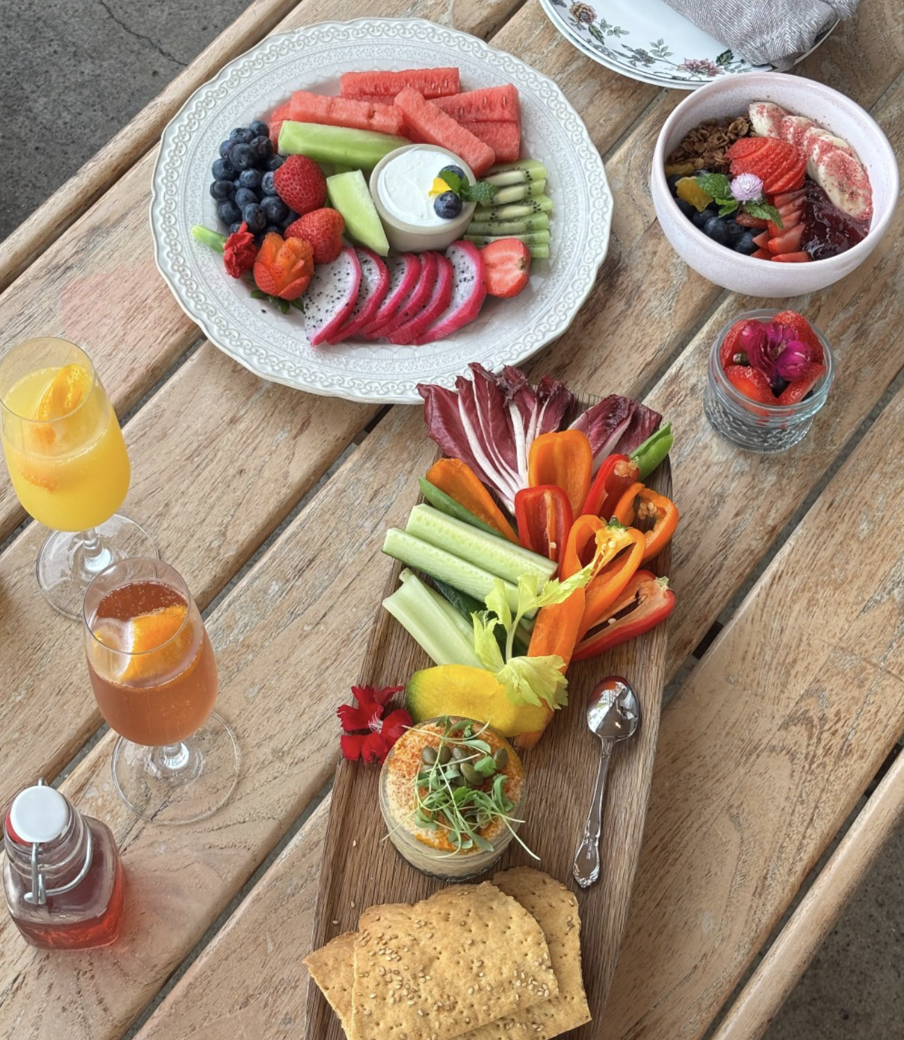 Breakfast spread on a wooden table with fruit, vegetables, and drinks.