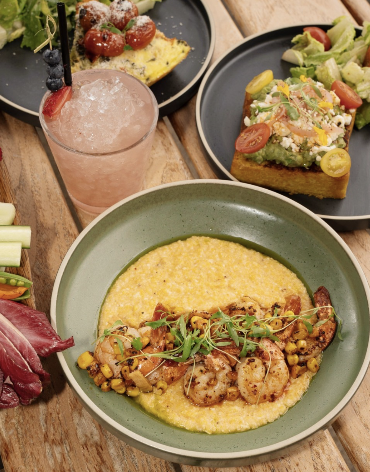 Shrimp and grits, avocado toast, egg dish, and pink cocktail.