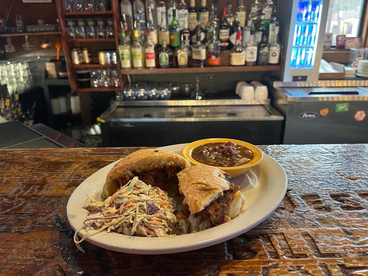 Pulled pork sandwich, coleslaw, and baked beans on a bar.