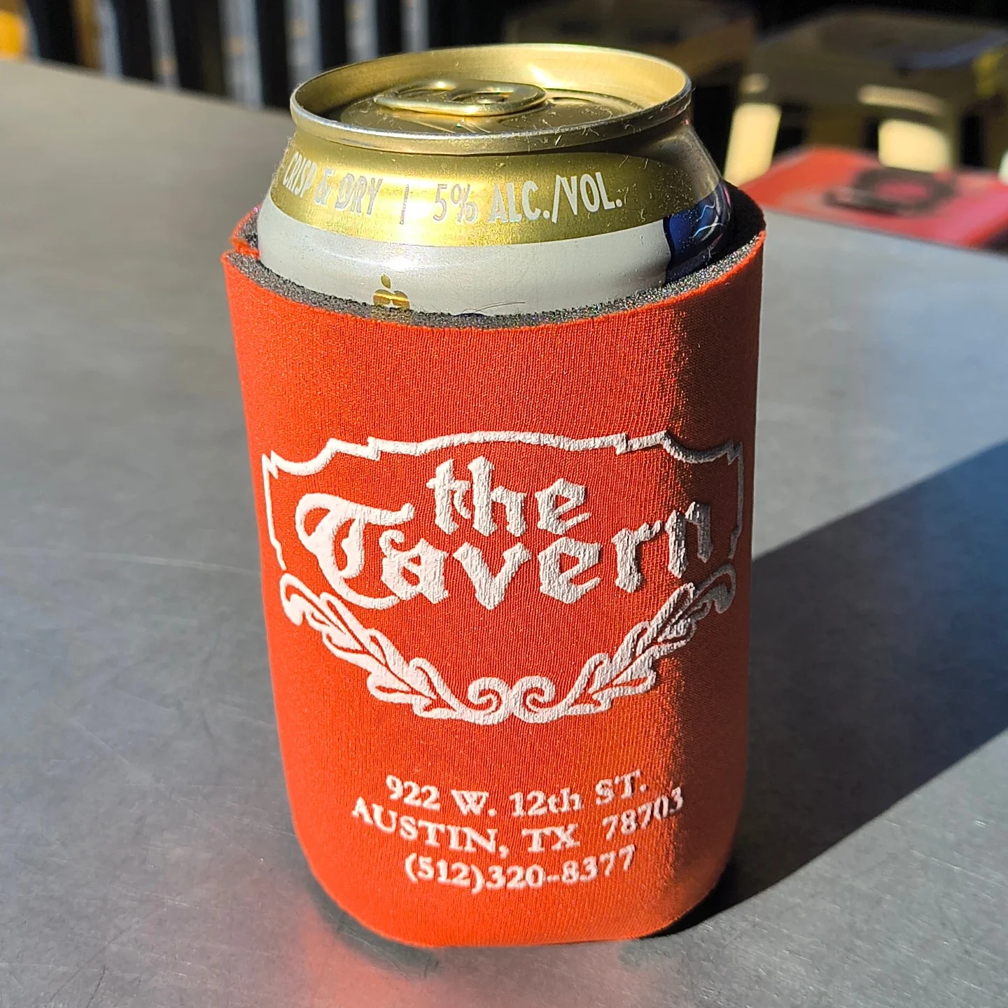 Orange "the Tavern" koozie holds a can of 5% alcohol.