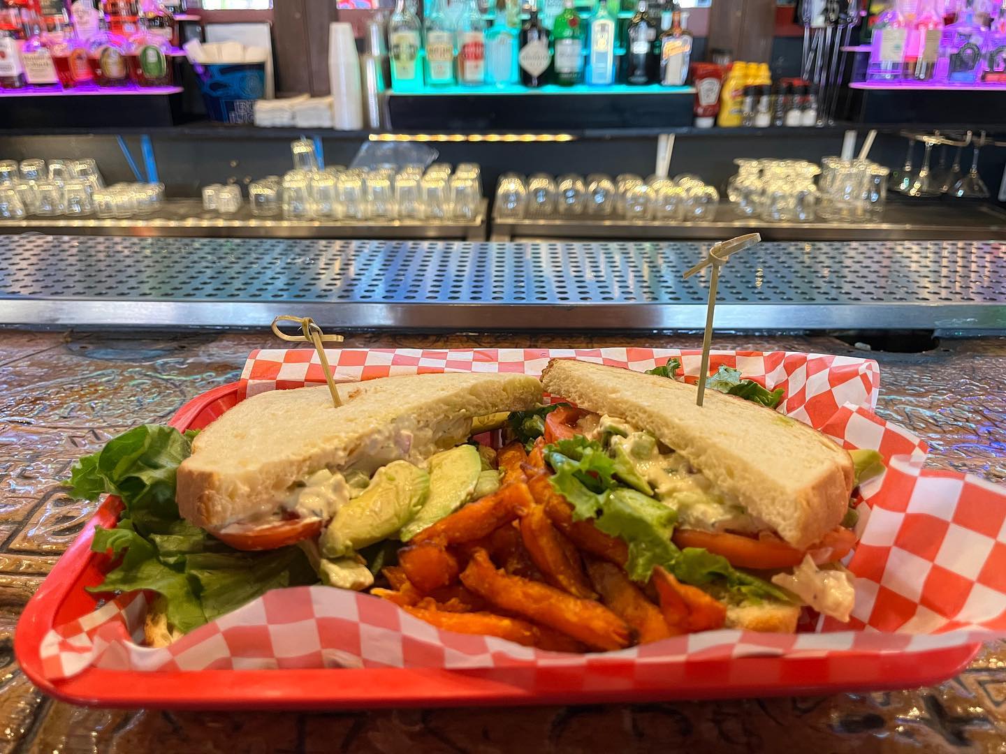 Creamy sandwich, avocado, lettuce, sweet potato fries at bar.