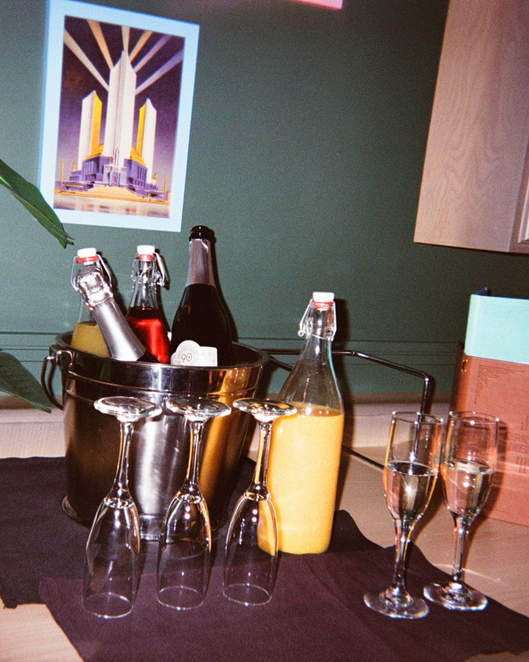 Ice bucket with bottles, juice, and various glasses on a table.