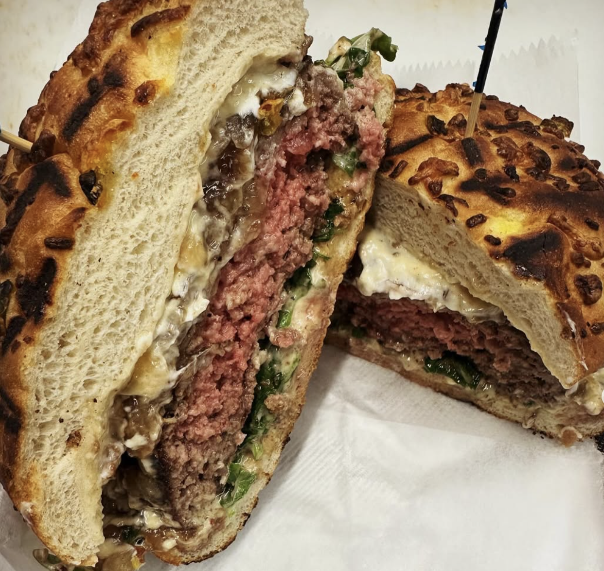 Sliced burger revealing a medium-rare patty, melted cheese, and caramelized onions.