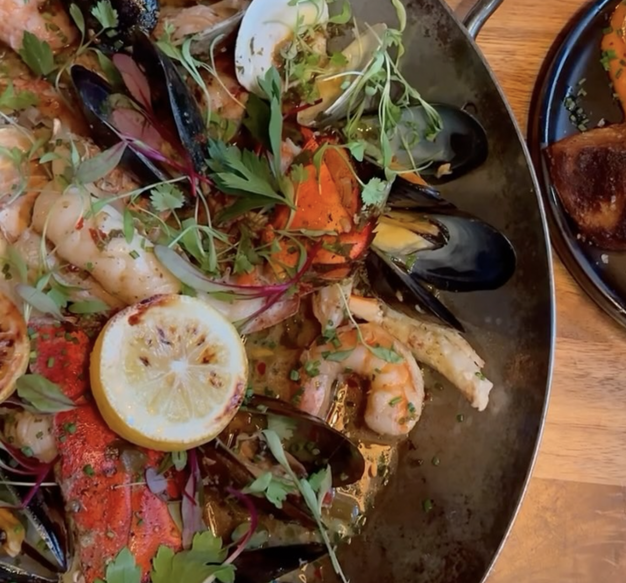 Pan of seafood with lobster, mussels, shrimp, clams, and lemon.