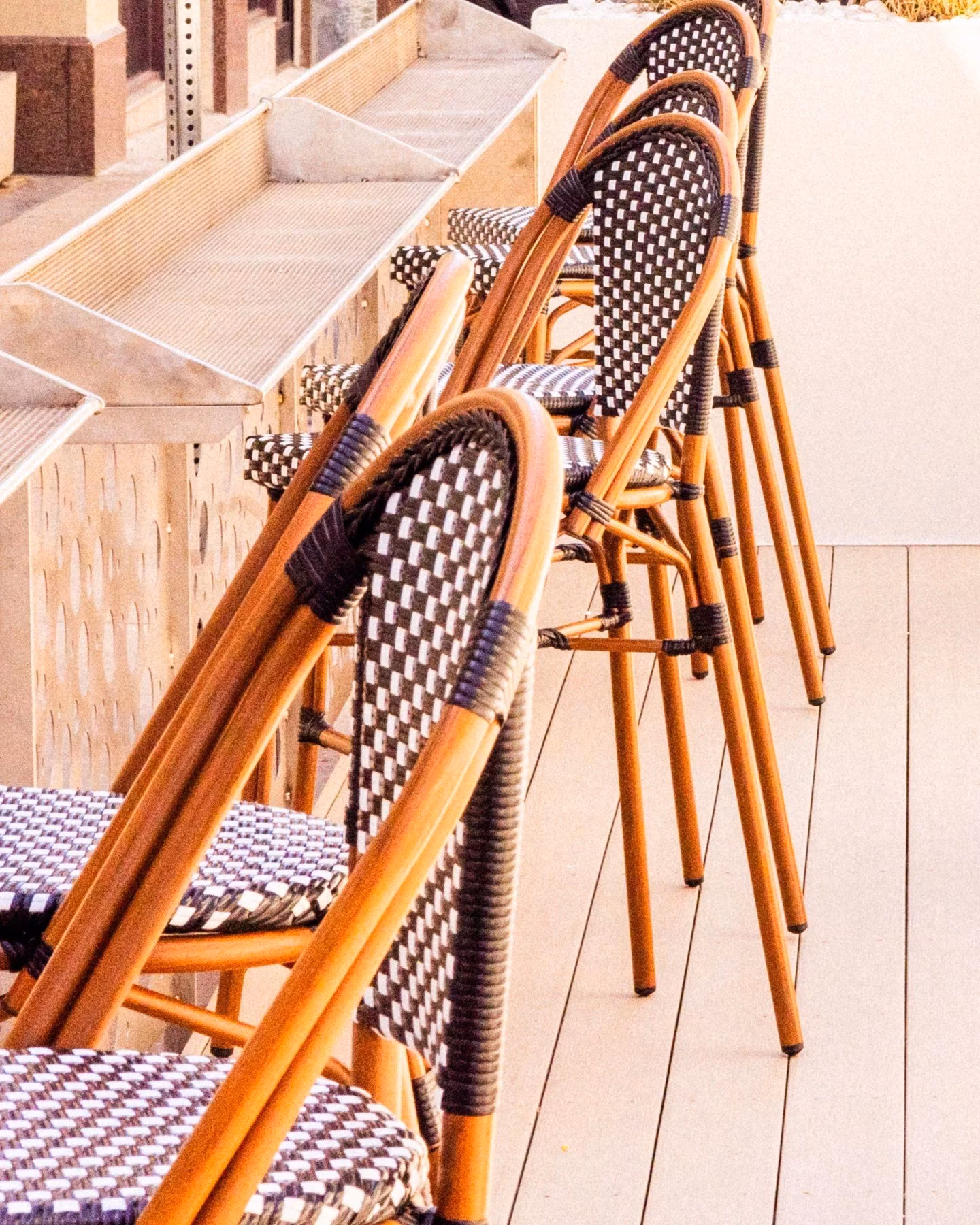 Row of outdoor cafe chairs with woven seats by a counter.