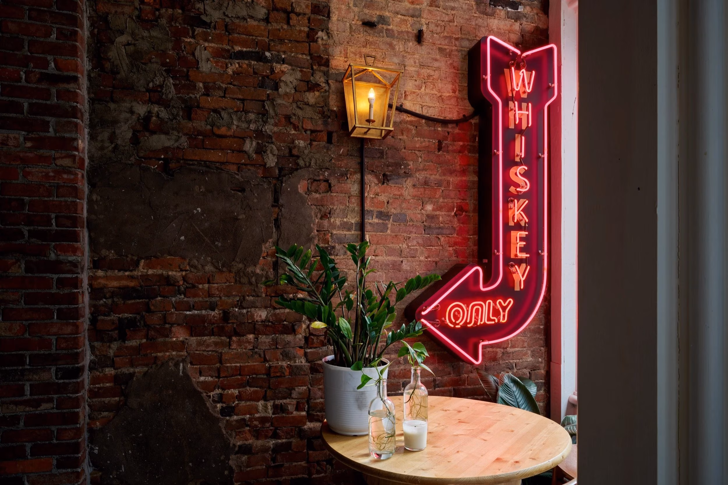 Red neon "Whiskey Only" sign and lantern on brick wall.