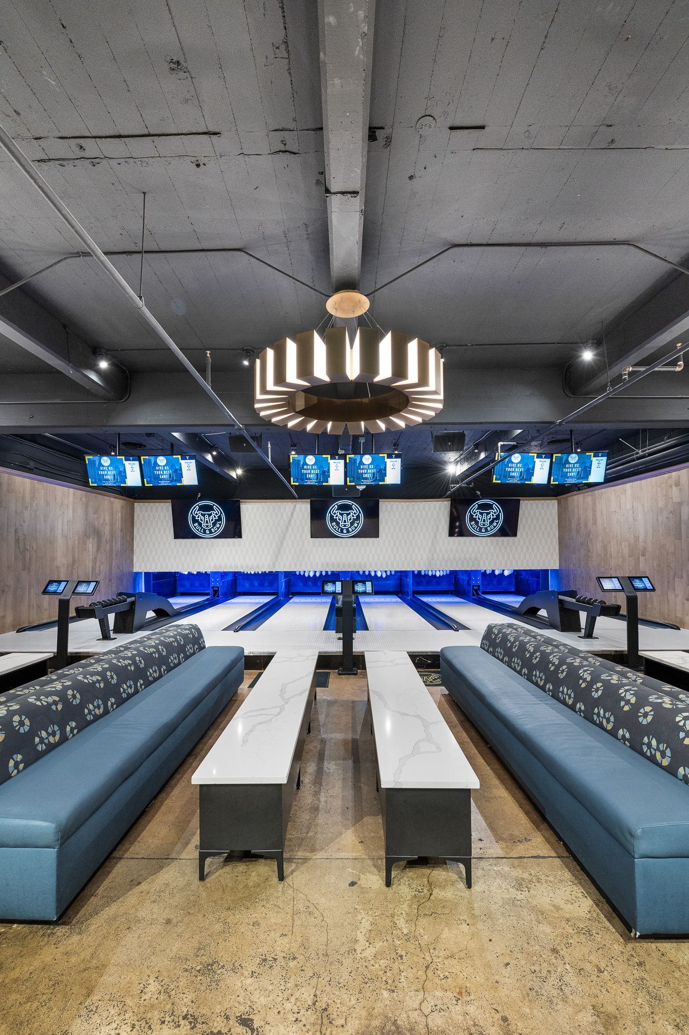Modern bowling alley interior with blue-lit lanes and long benches.