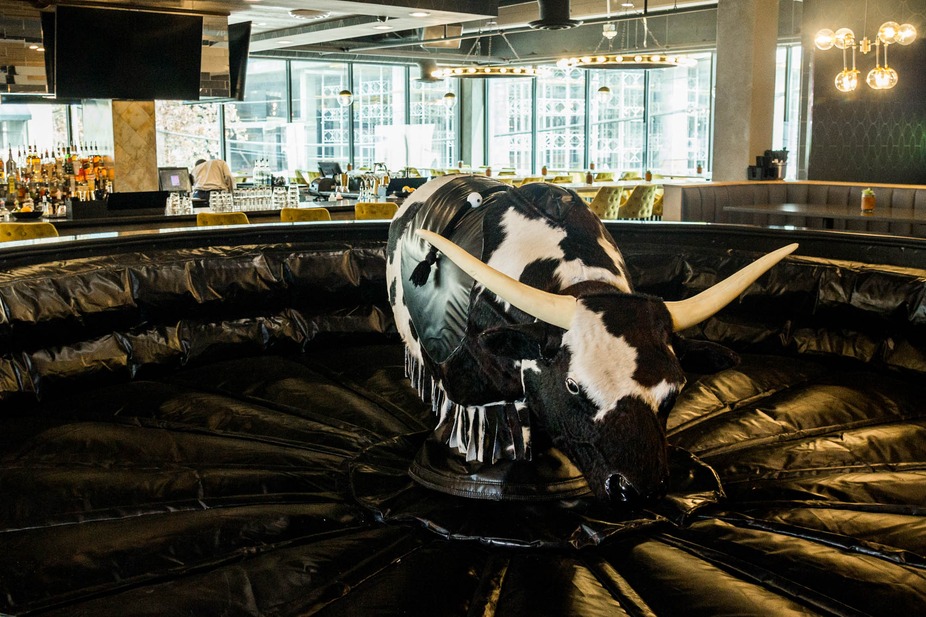 Mechanical bull on an inflatable mat inside a modern bar.