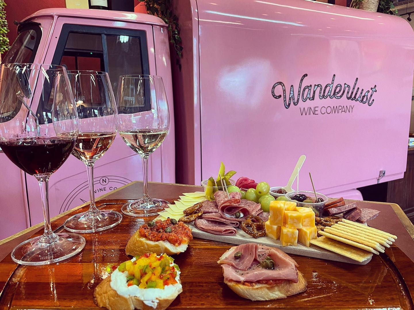 Three wines, charcuterie, appetizers, and a pink Wanderlust Wine Company truck.