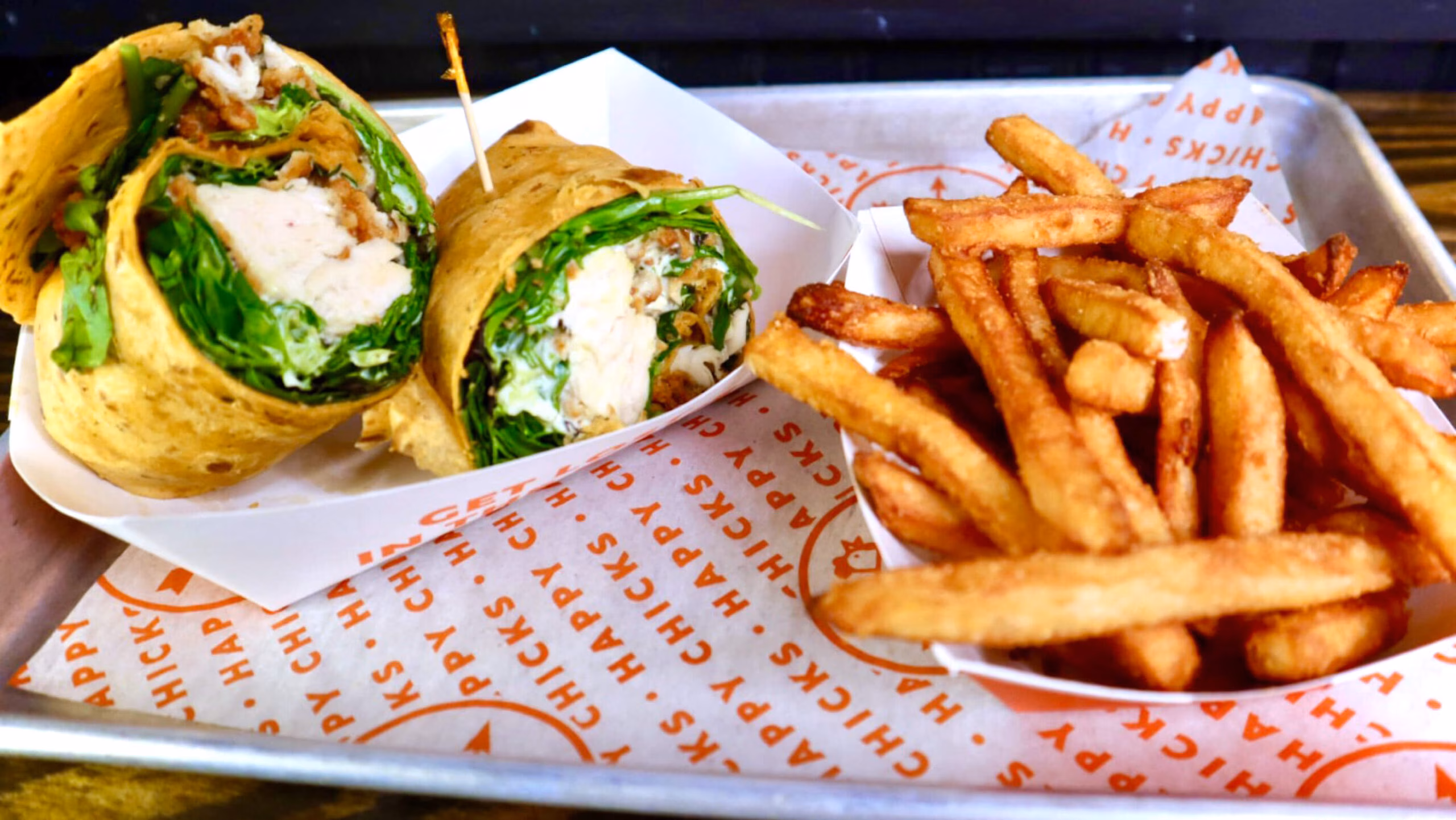 Two chicken and lettuce wraps with a side of french fries.