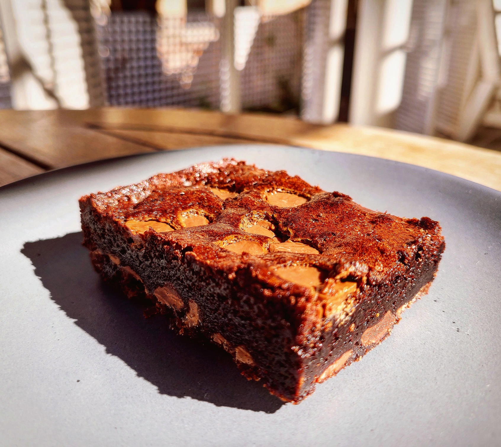 A chocolate brownie with chocolate chunks on a grey plate.