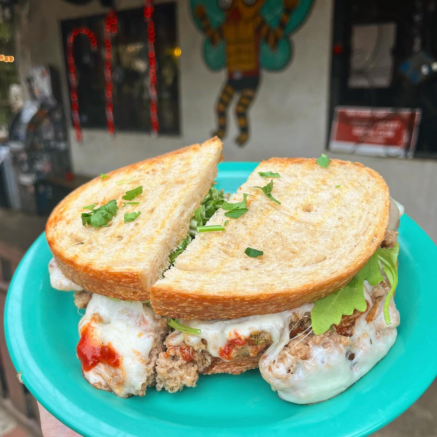 Meatball sandwich with melted cheese and toasted bread on a teal plate.