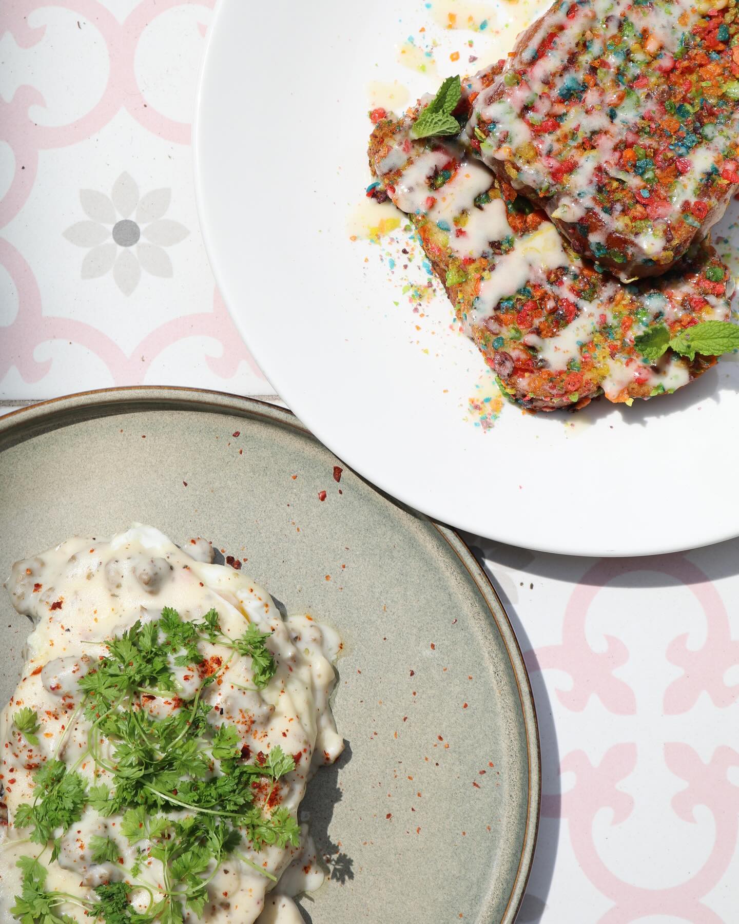 Colorful cereal French toast and biscuits with gravy on two plates.