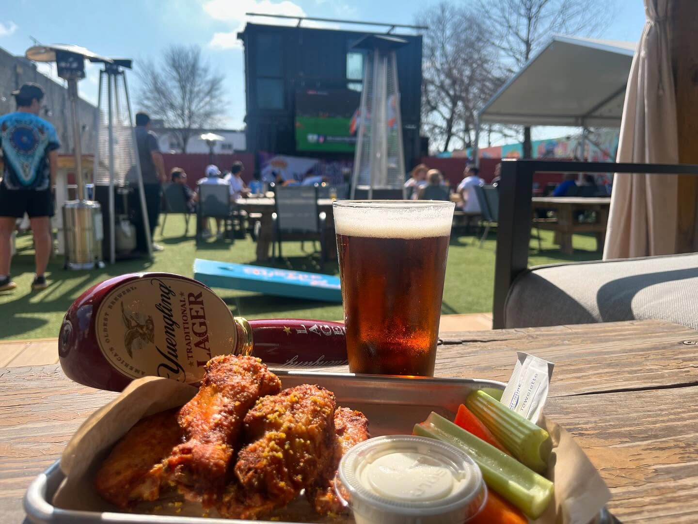 Chicken wings, beer, Yuengling tap handle on an outdoor patio table.
