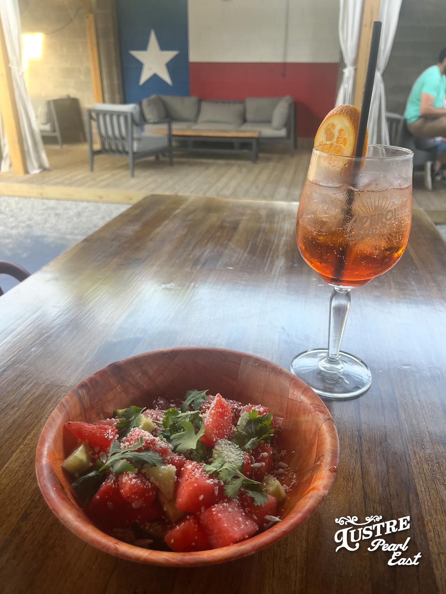 Watermelon salad and an orange cocktail on a wooden table.