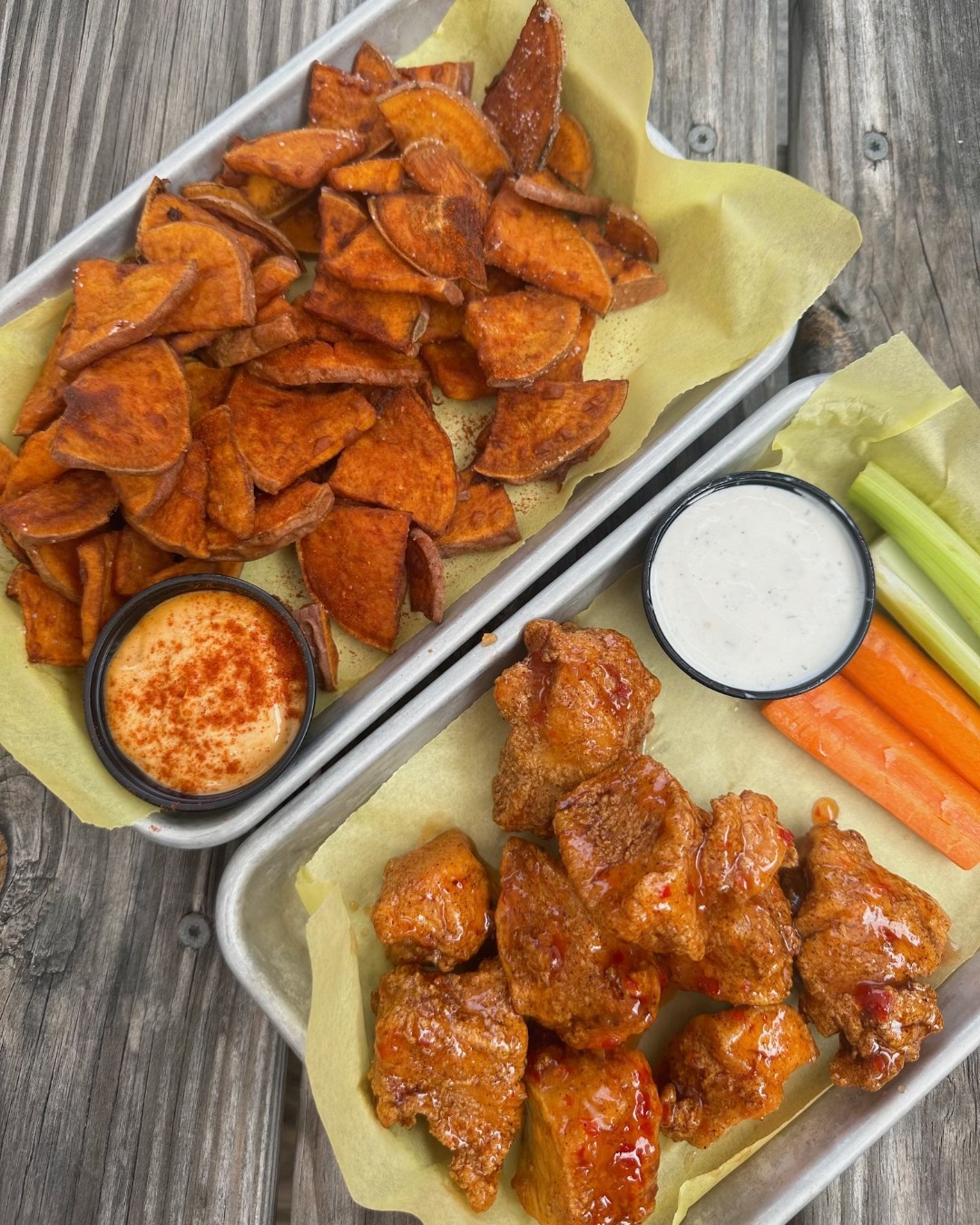 Sweet potato chips, sauced chicken, and vegetable sticks on trays.