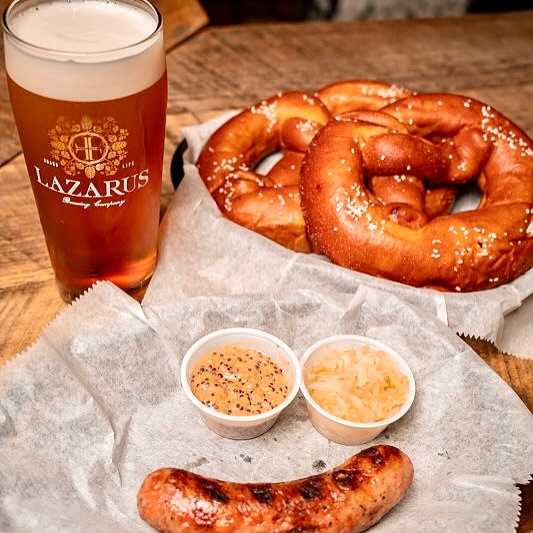 Glass of beer, soft pretzels, grilled sausage, mustard, and sauerkraut.