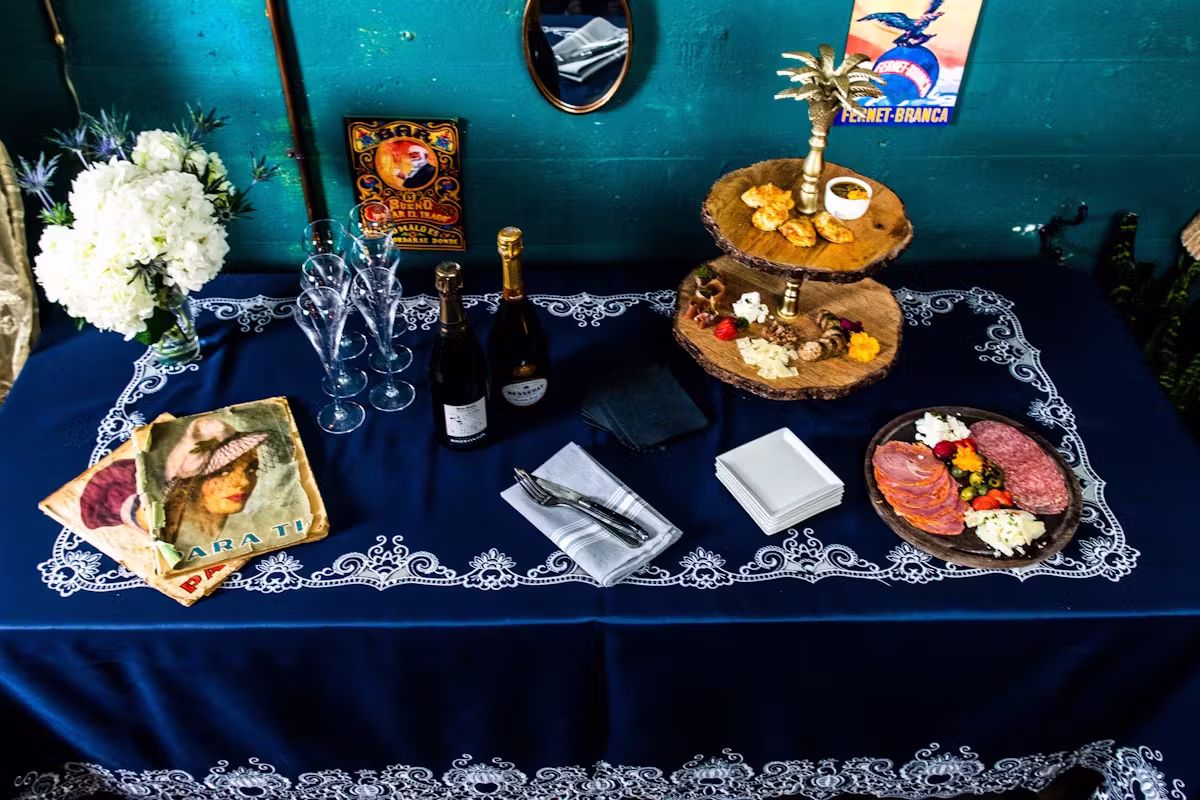 Party table with charcuterie, appetizers, champagne, and white flowers.