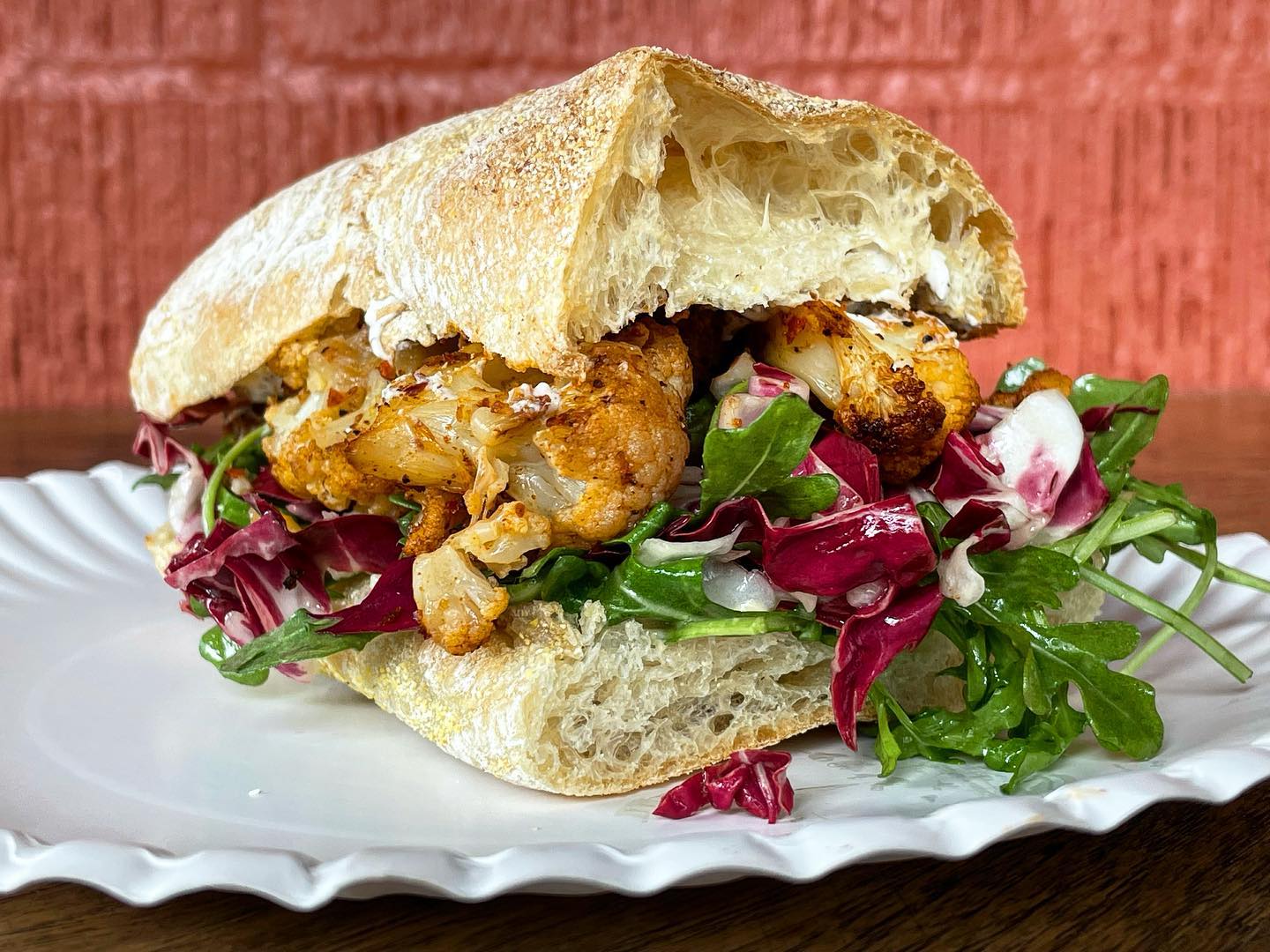 Roasted cauliflower sandwich with radicchio and arugula on a white plate.