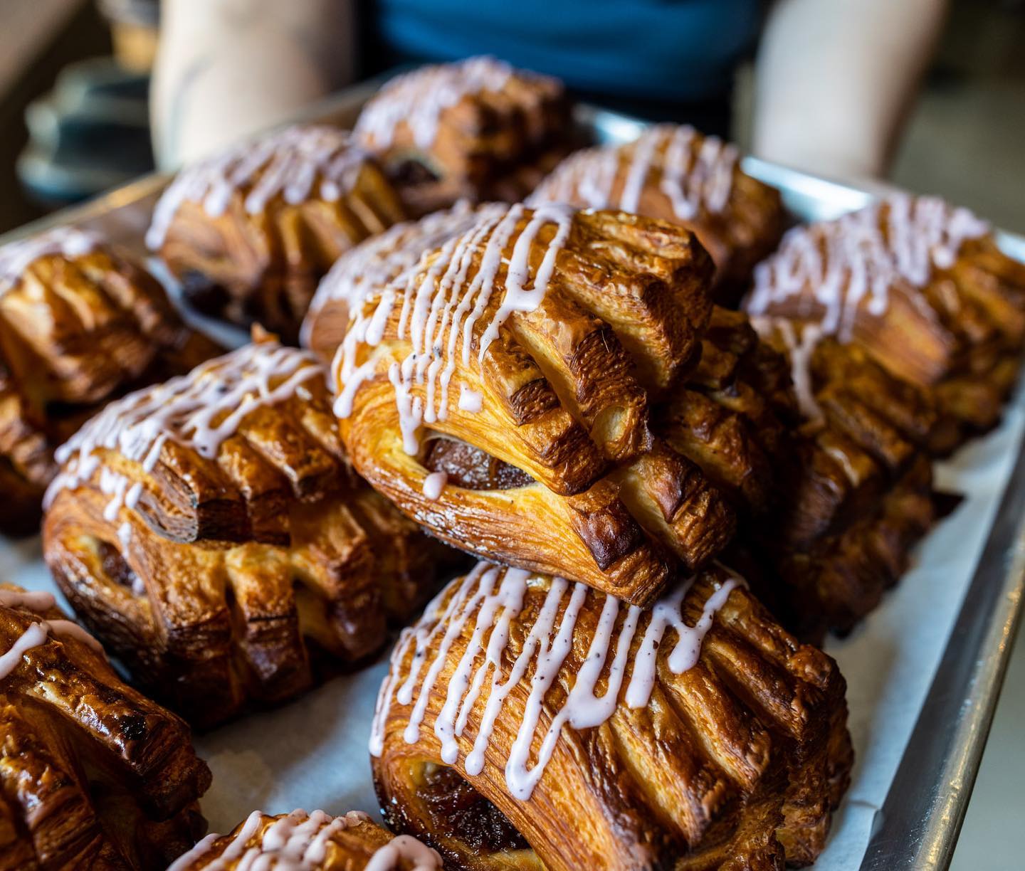 Flaky golden-brown pastries with light icing drizzle on a tray.