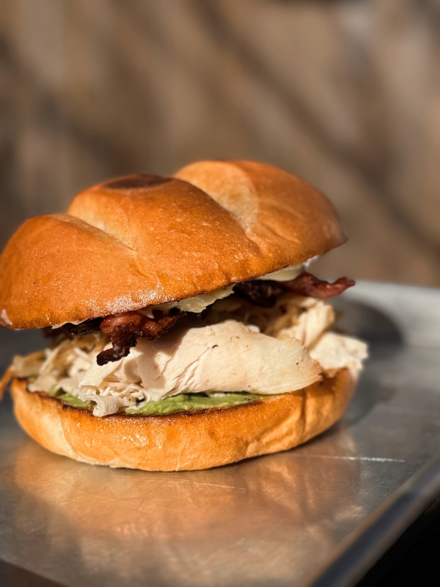 Turkey, bacon, and avocado sandwich on a golden bun.